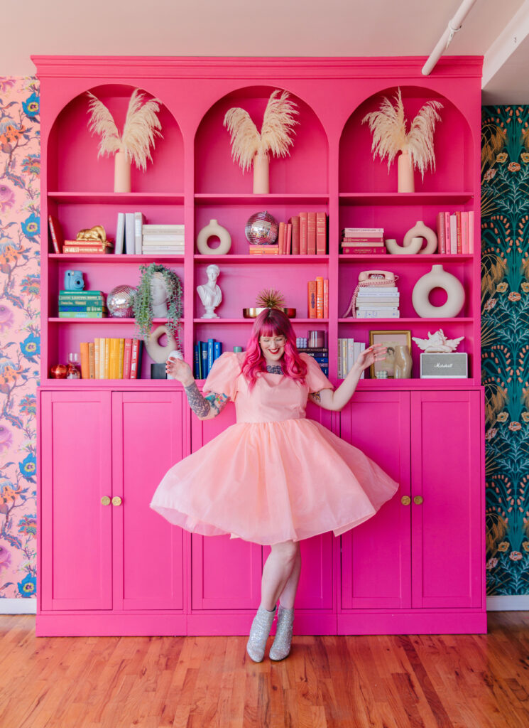 woman with pink tulle dress in front of pink bookcase